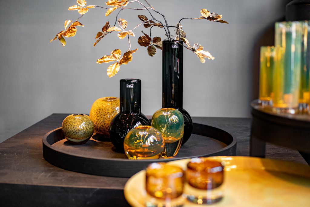 Grey Meryna vases and on the left golden ball vaese en on the right golden Hoola vases on a dark wooden table