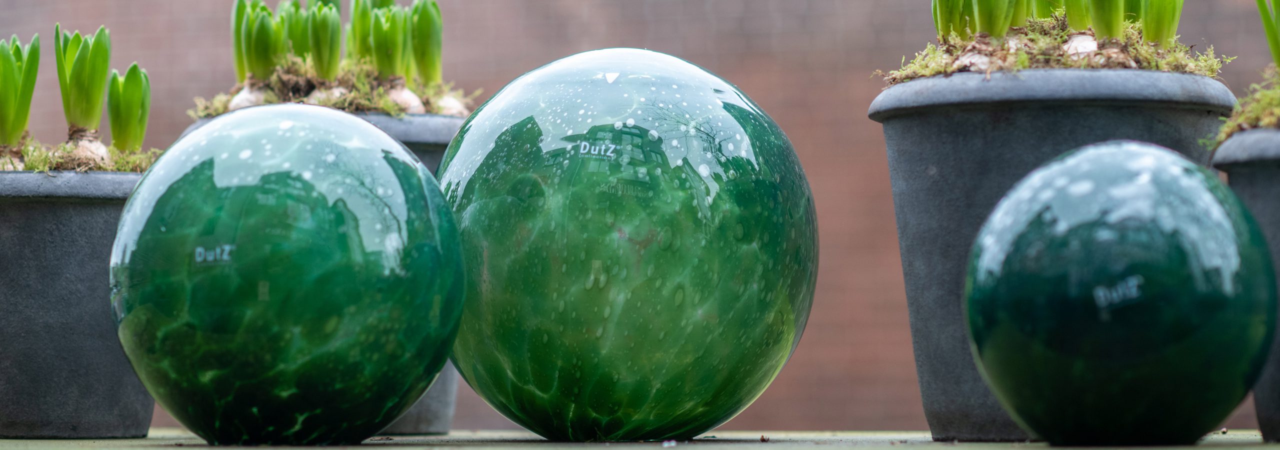 DutZ glass gardenballs in three sizes on a gardentable in the colour dark green